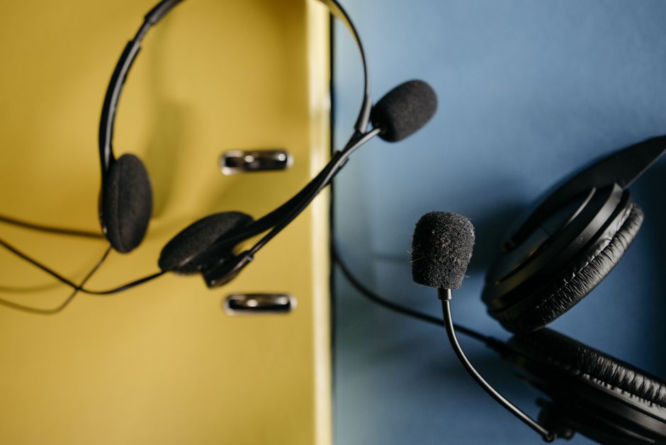 Close-up of headphones with attached microphones on a vibrant yellow and blue background, perfect for tech-related content.