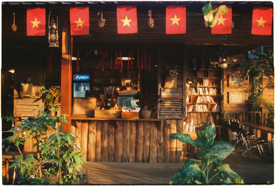 Charming outdoor café featuring red flags, vintage decor, and greenery, creating a warm, inviting ambiance.